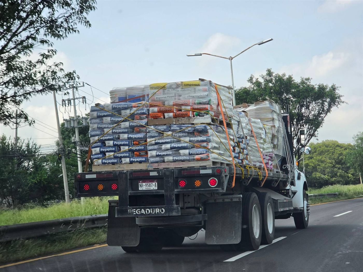 Tráiler con tarimas de Pegapiso y Estuco Pegaduro en carretera
